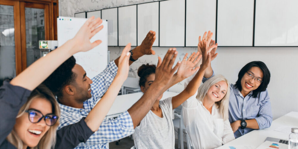 Attractive european girl waving hands with friends, happy for successful meeting. African and asian office workers having fun during conference and laughing..